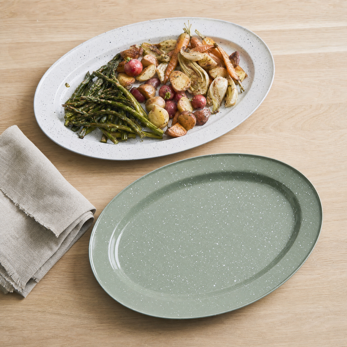 White speckled enamel oval platter with roast vegetables, sage platter beside